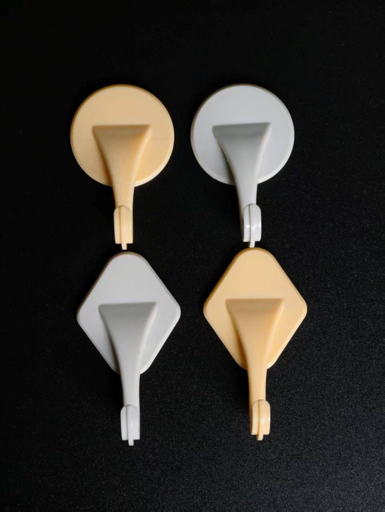 Round adhesive wall hooks in yellow and white on a smooth tile surface
